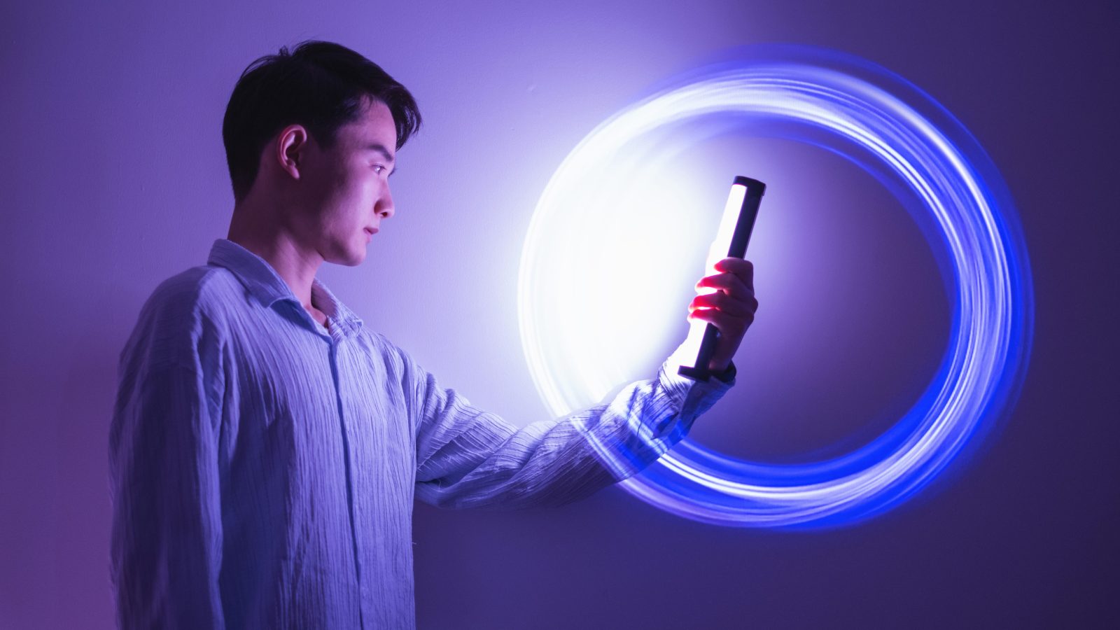 Young asian man holding glow stick on holographic background